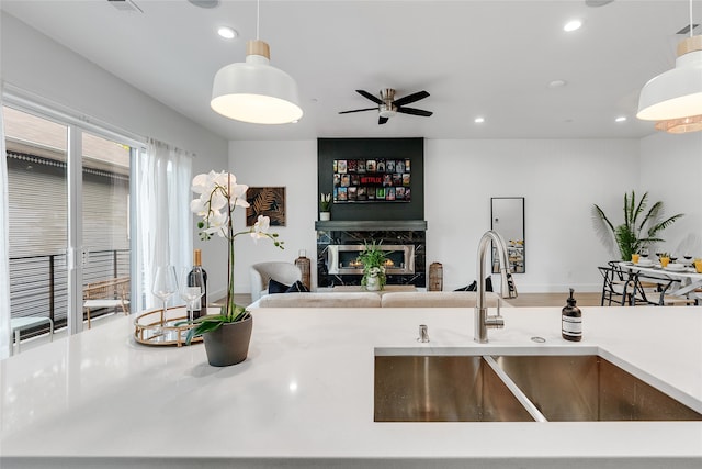 kitchen with ceiling fan, hanging light fixtures, sink, a fireplace, and hardwood / wood-style floors