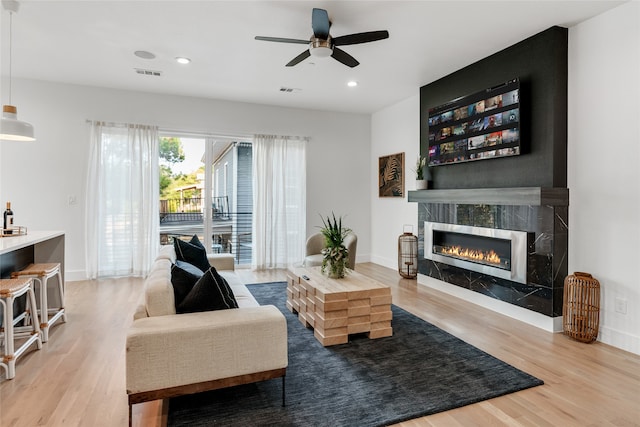 living room with light wood-type flooring, a fireplace, and ceiling fan