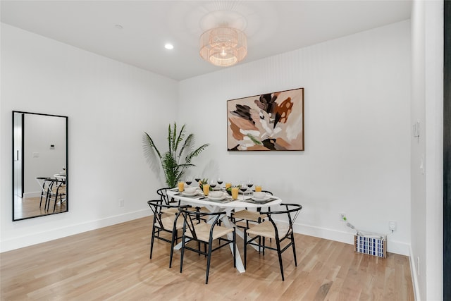 dining space with light hardwood / wood-style flooring and a chandelier