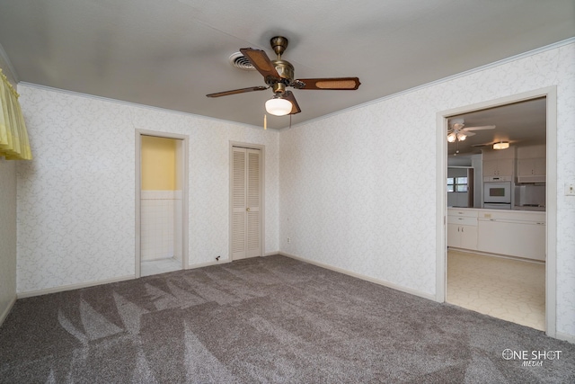 unfurnished bedroom with connected bathroom, carpet floors, ceiling fan, and ornamental molding