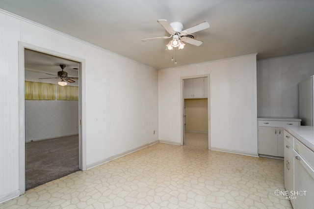 unfurnished bedroom with ceiling fan, a walk in closet, and crown molding