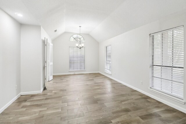 unfurnished dining area with vaulted ceiling, light wood finished floors, baseboards, visible vents, and an inviting chandelier