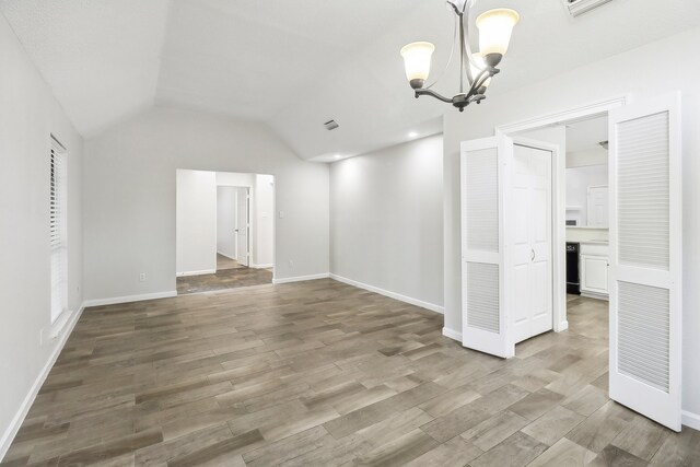 unfurnished dining area with wood-type flooring, lofted ceiling, and a chandelier