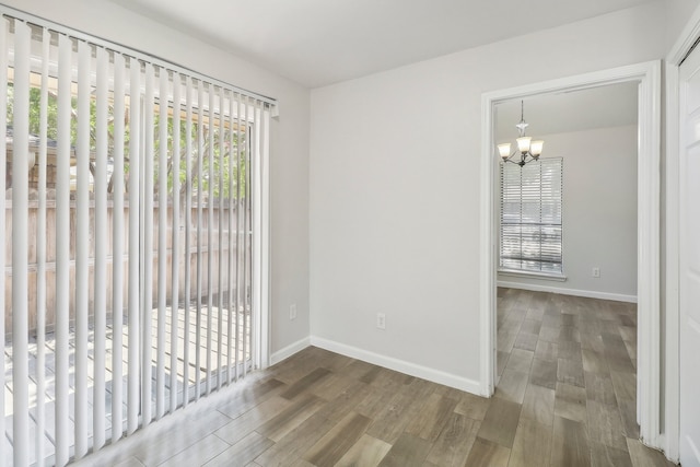 empty room featuring wood-type flooring and an inviting chandelier