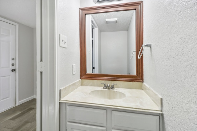 bathroom with a textured ceiling, wood-type flooring, and vanity