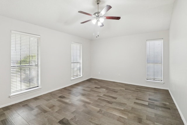 spare room featuring baseboards, wood finished floors, and a ceiling fan