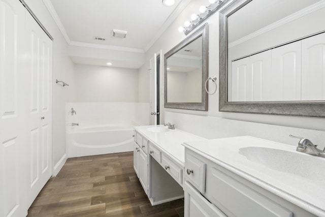 bathroom featuring vanity, hardwood / wood-style flooring, ornamental molding, and a bath