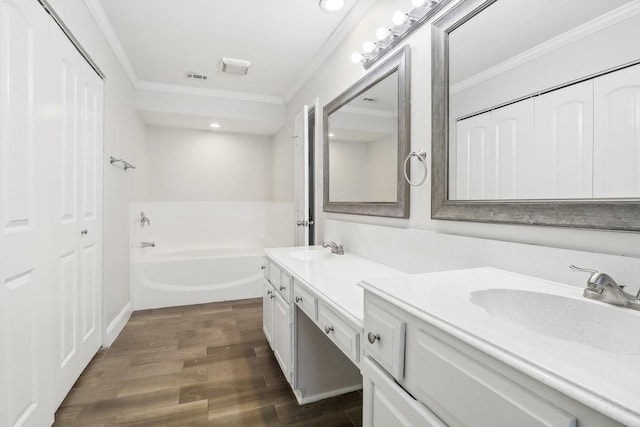 full bath with visible vents, double vanity, ornamental molding, wood finished floors, and a sink