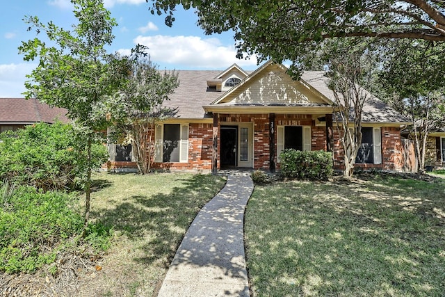 view of front facade with brick siding, a front lawn, and roof with shingles