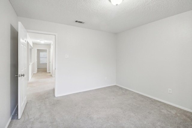 carpeted spare room with baseboards, a textured ceiling, and visible vents