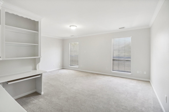 spare room featuring crown molding, a healthy amount of sunlight, light colored carpet, and visible vents