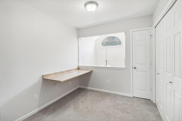 unfurnished bedroom with a closet, carpet flooring, a textured ceiling, and baseboards