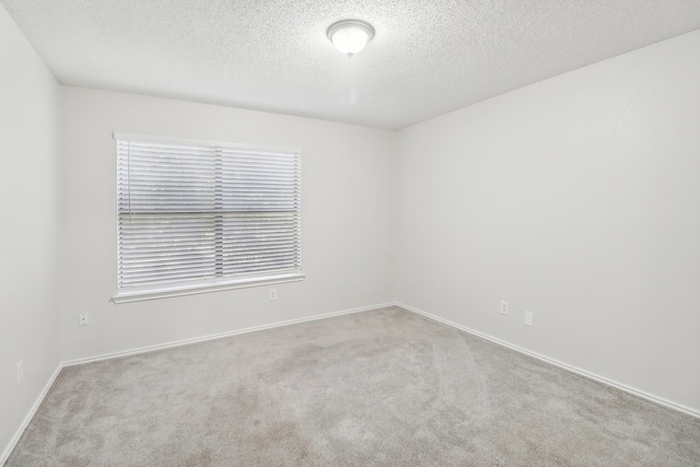 carpeted empty room featuring a textured ceiling