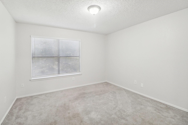 unfurnished room featuring baseboards, carpet flooring, and a textured ceiling