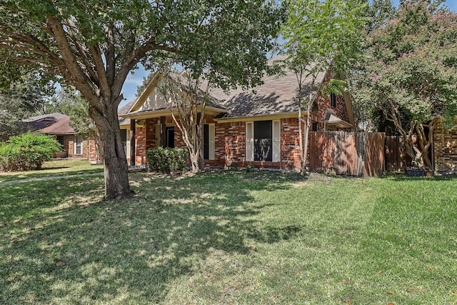 view of front of house featuring brick siding, a front yard, a shingled roof, and fence