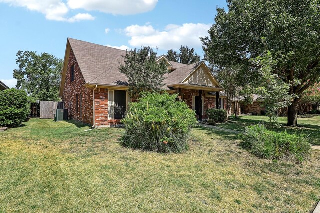 view of front facade with brick siding, a front lawn, central AC, and roof with shingles