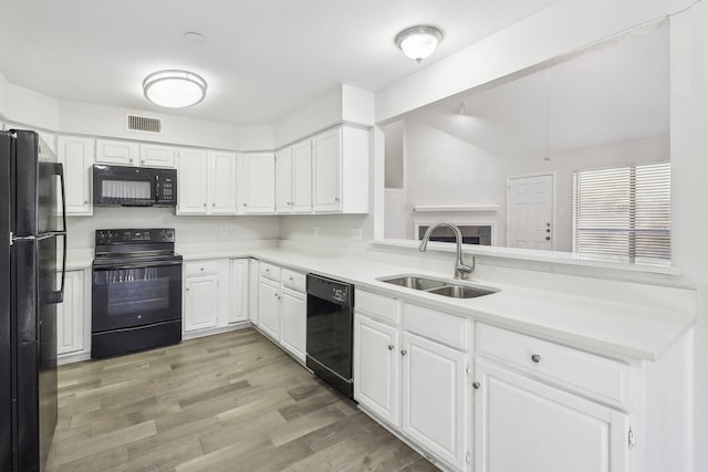 kitchen with sink, white cabinets, kitchen peninsula, light hardwood / wood-style flooring, and black appliances