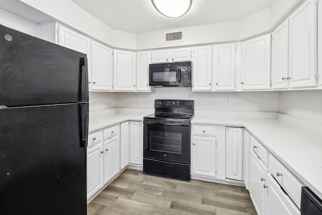 kitchen with light hardwood / wood-style flooring, white cabinets, and black appliances