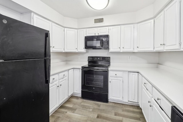 kitchen featuring visible vents, white cabinets, and black appliances