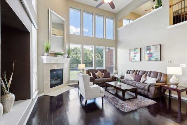 living room featuring a tile fireplace, a towering ceiling, ceiling fan, and hardwood / wood-style flooring