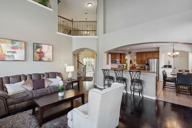 living room with a high ceiling, light hardwood / wood-style floors, and a notable chandelier