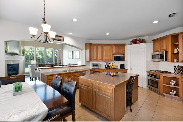 kitchen featuring sink, decorative light fixtures, appliances with stainless steel finishes, a center island, and a notable chandelier