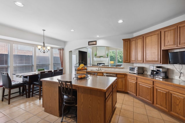 kitchen with a kitchen island, a breakfast bar area, light tile patterned floors, pendant lighting, and a chandelier