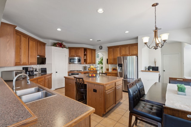 kitchen with appliances with stainless steel finishes, pendant lighting, a center island, sink, and a notable chandelier