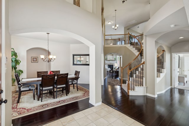 entryway with an inviting chandelier, light wood-type flooring, and a towering ceiling