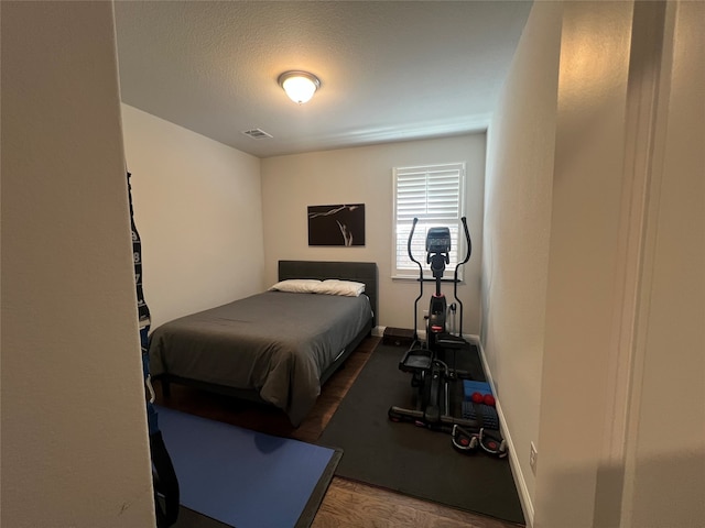 bedroom with a textured ceiling and dark wood-type flooring