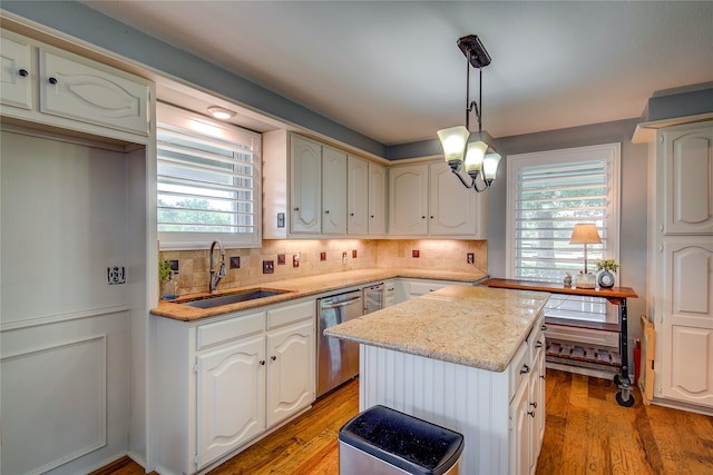 kitchen featuring backsplash, a center island, stainless steel dishwasher, light wood-style floors, and a sink