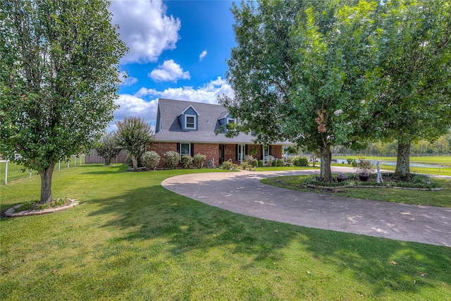 cape cod house with concrete driveway, brick siding, and a front yard