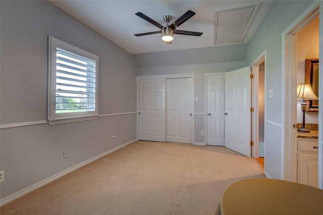 bedroom with light carpet, a ceiling fan, attic access, and baseboards