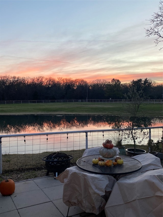 patio terrace at dusk featuring a water view