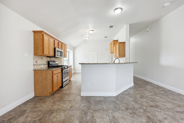 kitchen featuring light stone counters, light tile patterned floors, backsplash, appliances with stainless steel finishes, and vaulted ceiling