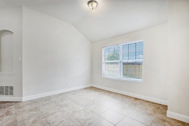 unfurnished room with vaulted ceiling and light tile patterned flooring