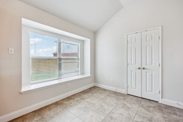 unfurnished bedroom with vaulted ceiling, a closet, and light tile patterned floors