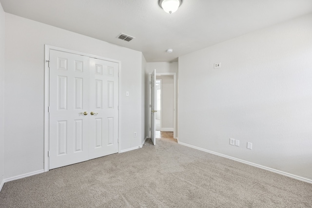 unfurnished bedroom with light carpet and a closet