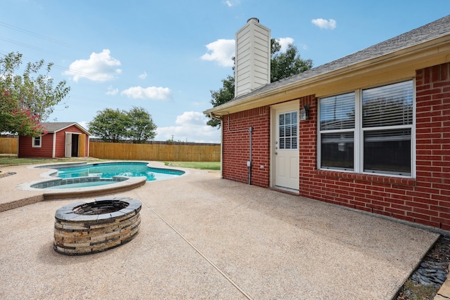 view of swimming pool with a storage unit, a fire pit, and a patio area