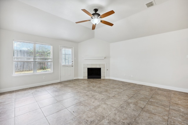 unfurnished living room featuring ceiling fan, lofted ceiling, a tiled fireplace, and light tile patterned floors