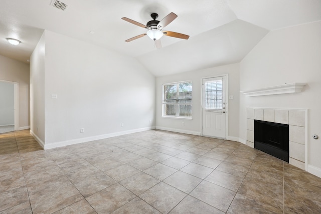 unfurnished living room with ceiling fan, light tile patterned flooring, vaulted ceiling, and a tile fireplace