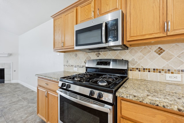 kitchen featuring decorative backsplash, light tile patterned flooring, appliances with stainless steel finishes, and light stone countertops