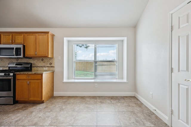 kitchen featuring light stone counters, appliances with stainless steel finishes, backsplash, and light tile patterned floors