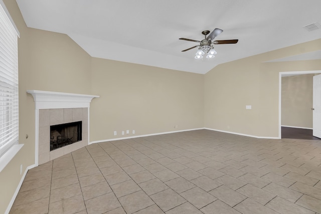 unfurnished living room with ceiling fan, lofted ceiling, light tile patterned floors, plenty of natural light, and a tile fireplace