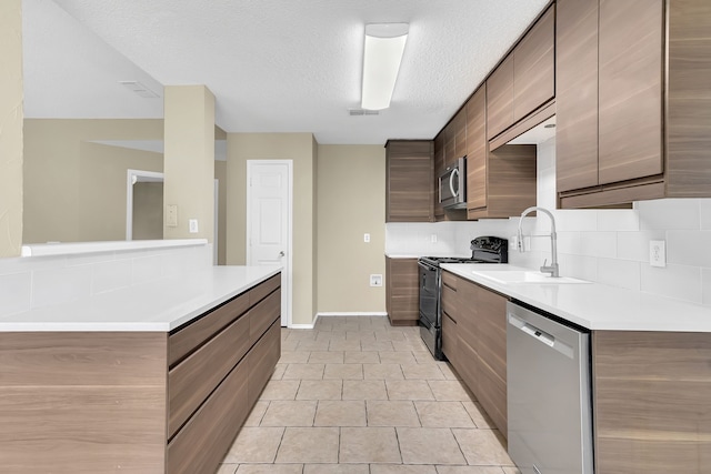 kitchen with a textured ceiling, sink, decorative backsplash, stainless steel appliances, and light tile patterned floors