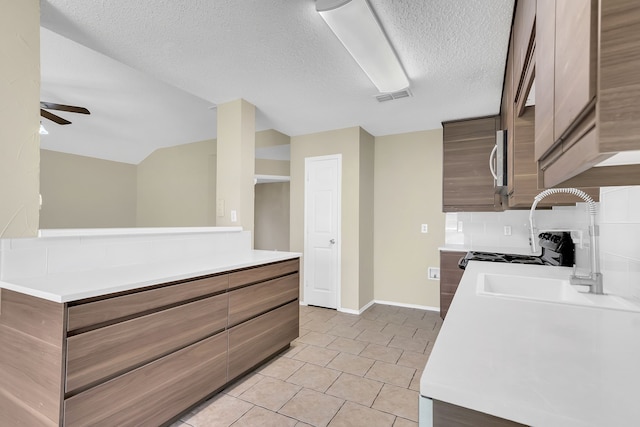 kitchen featuring a textured ceiling, decorative backsplash, vaulted ceiling, and ceiling fan