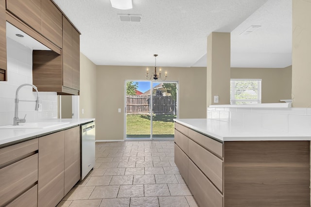 kitchen featuring backsplash, dishwasher, a textured ceiling, sink, and a chandelier