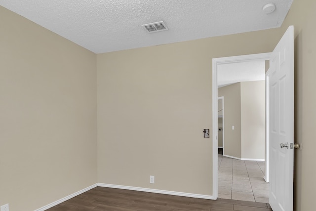 unfurnished room featuring light hardwood / wood-style floors and a textured ceiling