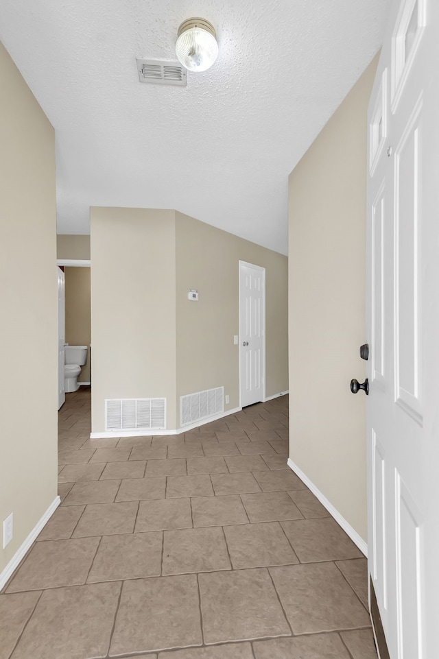 spare room with a textured ceiling and light tile patterned flooring