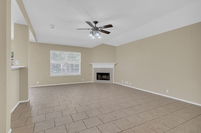 unfurnished living room with ceiling fan, a tile fireplace, light tile patterned flooring, and a textured ceiling